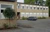 SAK00256_Stockholm, Bredäng, Tankebyggarorden 2, Björksätravägen 22-48.

I bildens högra del; tvåvåningsbyggnaden på skolgårdens västra sida. Foto från sydost. Lägg märke till fönstrens galler och de plåtinklädda övre lufterna. 