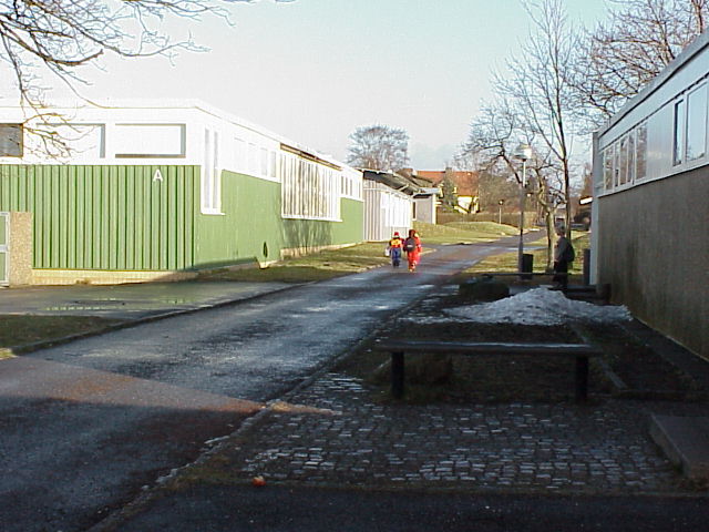 Vy mot nordost längs skolans utsida. Gångvägen leder till ett näraliggande egnahemsområde. Till höger skymtar en av gymnastikbyggnaderna på andra sidan gångvägen.