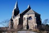 Kyrkan ligger på en kyrkoterrass på berget ovanför begravningsplatsen. 