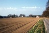Kyrkplatsen från öster, omgiven av jordbruksmark och med den intilliggande Resteröds gård.