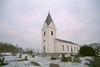 Valinge kyrka med omgivande kyrkogård sedd från sydväst.