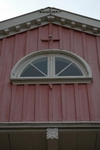 Gavelfältet ovan verandan har ett lunettfönster och takfoten markeras med en tandsnittsfris.
