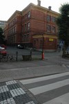 Nya Elementarläroverket för flickor, baksidans fasad mot Gustavsgatan, kortsidan mot Vasagatan. Skolgården omges av gjutjärnsstaket och planterade lövträd.