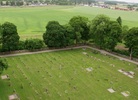 Överblick över ena hörnet av kyrkogården med omgivande kallmurad gråstensmur.
