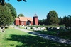 Ölsremma kyrka med klockstapel och omgivande begravningsplats sedd från SV
