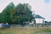 Ambjörnarps kyrka med omgivande kyrkogård sedd från parkeringsplatsen i öster.