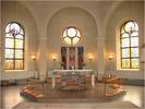 Koret med fristånde altare, åttakantig altaravsats och fönster med glasmålningar. 