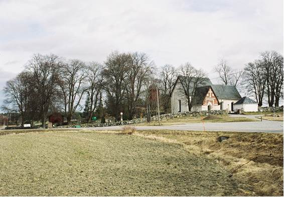 Kyrkan med muromgärdad kyrkogård som sträcker sig ned till landsvägen.