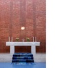 Altarbord med altarprydnad på tegelmuren, en framställning av Den helige Ande i form av trons ”Heliga lågor” utförd i ofärgat glas med indirekt belysning av Erik Höglund. © erik höglund/bus 2008