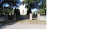 Kyrkogårdens ingång i väster med grindar i svartmålat
smide. Fram till kyrkan leder en grusgång kantad av
höga tujor. (KI Källa kyrkog 001)