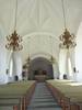 Ljuskronornas form är det enda dramatiska i kyrkorummet, som annars präglas av vita rena ytor, de höga medeltidsinspirerade stjärnvalven och den imponerande långa och harmoniskt jämna raden av bänkar, färgsatta i dova toner. Helhetsintrycket är lugnoch värdigt. Koret skiljs från långhugenom en markerad triumfbåge. Det breda altaret och altartavlan lyses vanligtvis upp av ett söderfönster i koret. Vid karaktäriseringsbesöket var persiennen fördragen.