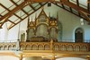 Parti av kyrkorummets västra del med orgeln och del av läktarbröstningen.