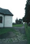 Den medeltida kyrkans utbredning finns markerad i marken, söder om kyrkan. Klockstapeln ligger stdost om kyrkan.
