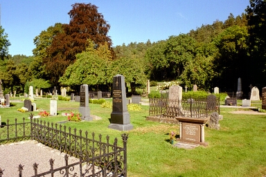 Kyrkogården öster om Västra Tunhems kyrka präglas av sirliga järnstaket, höga gravstenar och hängaskar.