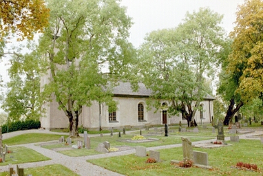 Vassända-Naglums kyrka. Kyrkogården kantas av åldriga askar och lönnar.