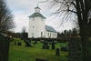 Håcksviks kyrka med omgivande begravningsplats sedd från sydväst.