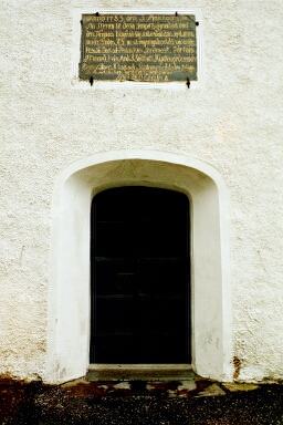 Västra porten i Toarps kyrka, samt däröver en inskriptionssten om kyrkans uppförande 1783. 