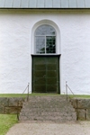 Södra porten i Toarps kyrka i fonden av vägen upp genom kyrkogården.