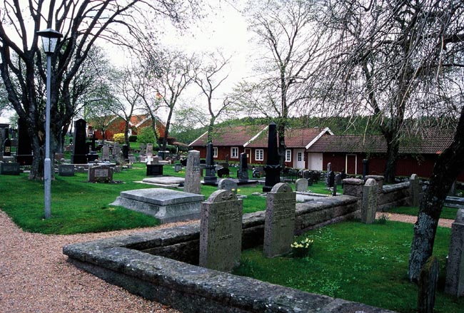 Östra delen av kyrkogården, med ekonomibyggnader och församlingshem i bakgrunden.