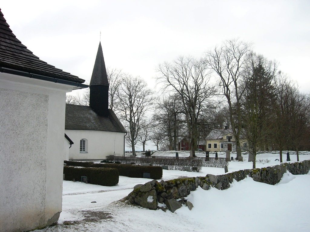Skeppsås kyrka med klockbod och prästgården i bakgrunden, från nordöst.