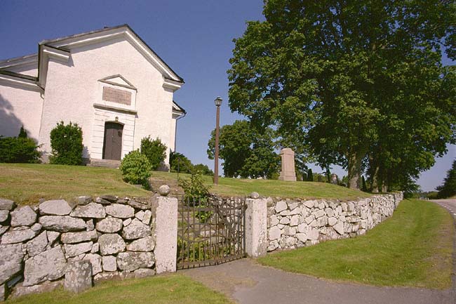 Sakristians östra fasad samt del av kyrkogårdsmur med grind.