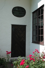 Flyglarnas entréer har ett ovalt fönster med blyinfattade färgade rutor ovan dörren