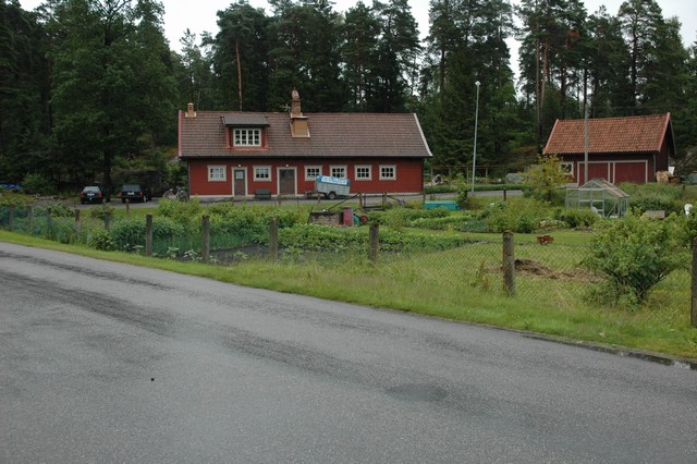 Västergärdet på Olidan: i anslutning till inägan med koloniträdgårdar ligger två rödfärgade trähus, det högra en stallbyggnad.