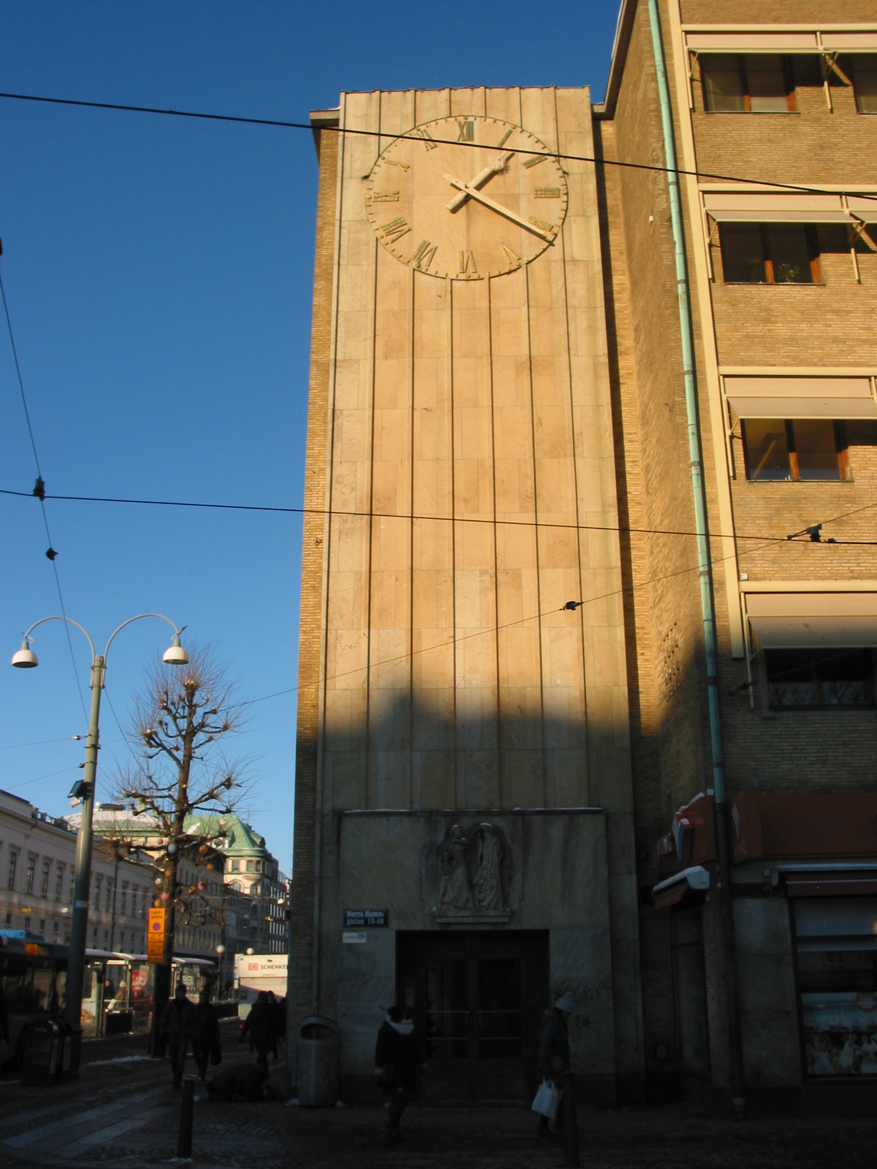 Sandstensreliefen över huvudentrén av I Johnson samt den förgyllda urtavlan. Ett fasadparti som utgör den funktionalistiska byggnadens huvudsakliga dekor.