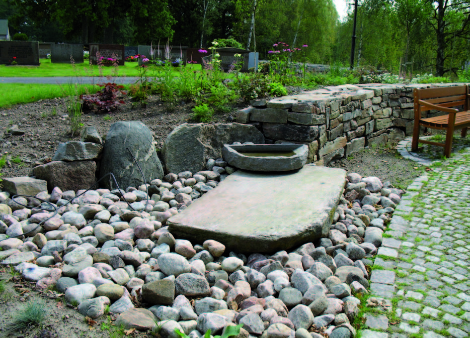 Vid muren i minneslunden finns ett litet område med avrundade
stenar och en större stenhäll placerad.