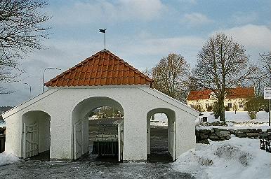 Stigluckan till Sätila kyrka i den norra kyrkogårdsmuren med prästgården i fonden, från S.
