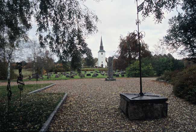 Blomskogs kyrka med den gamla kyrkplatsen i förgrunden.