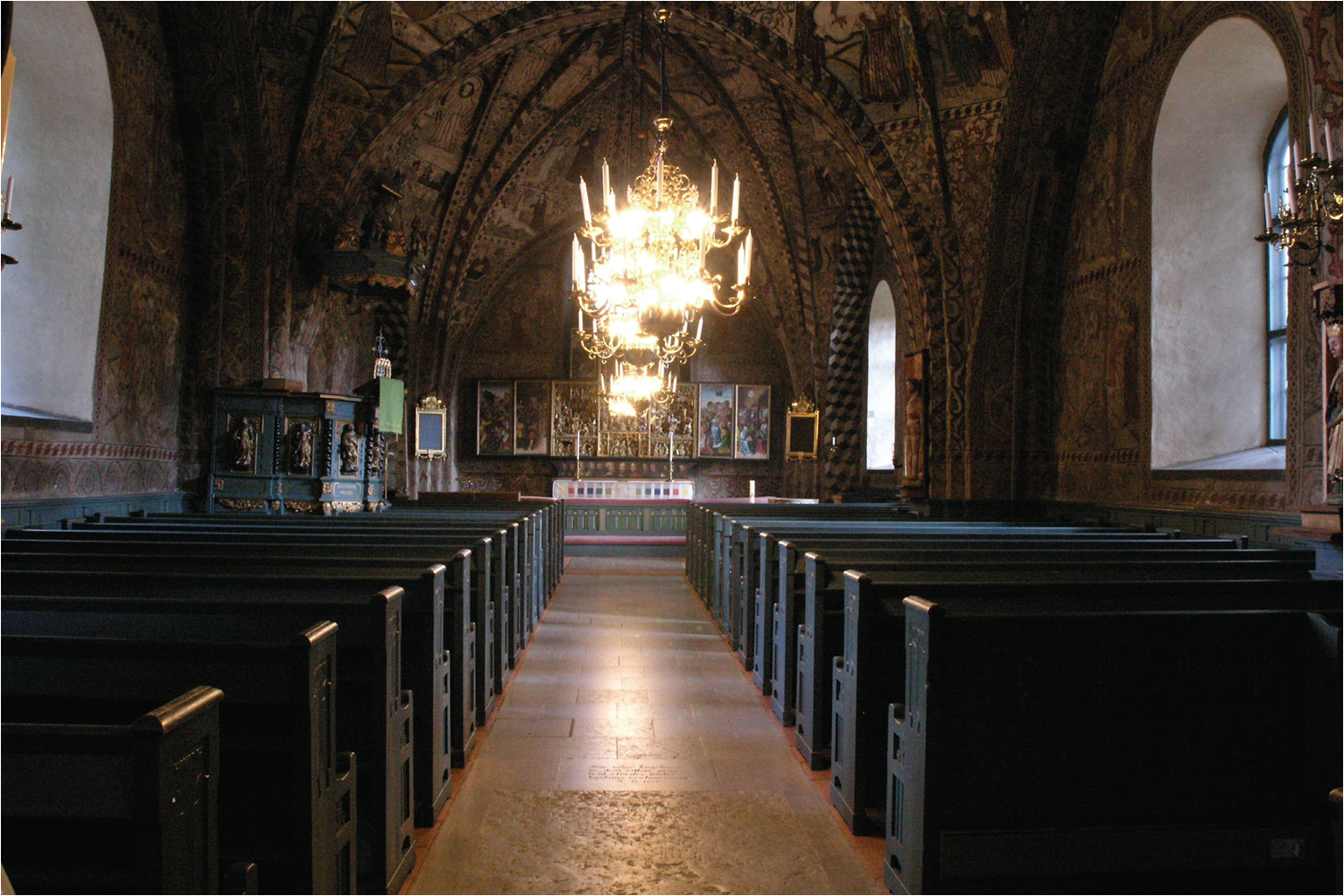 Koret från väster med medeltida altarskåp och dopfunt.