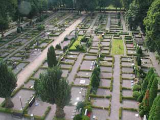 Vy över en stor del av kyrkogårdens äldsta del som är
belagd med grus. 