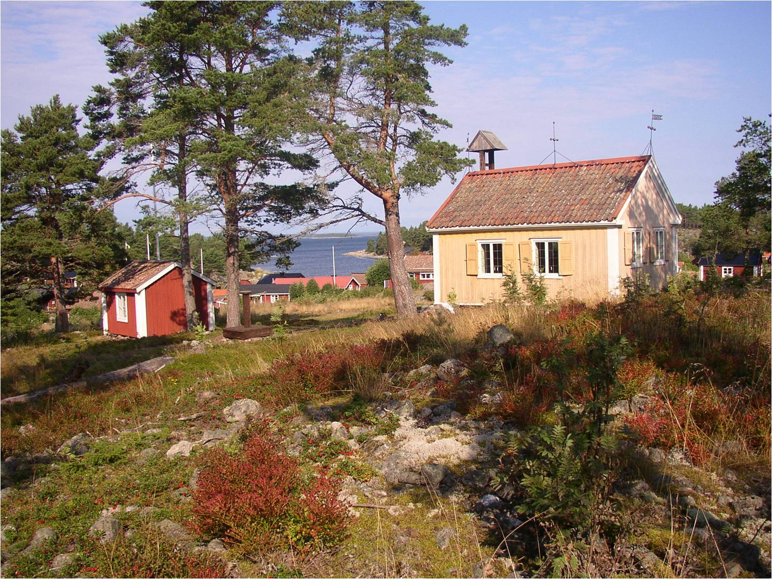 Prästkammaren och kapellet på Kråkön med fiskeläget vid den naturliga havsviken i bakgrunden. Till höger i bild skymtar även den gemensamma mangelboden. 
