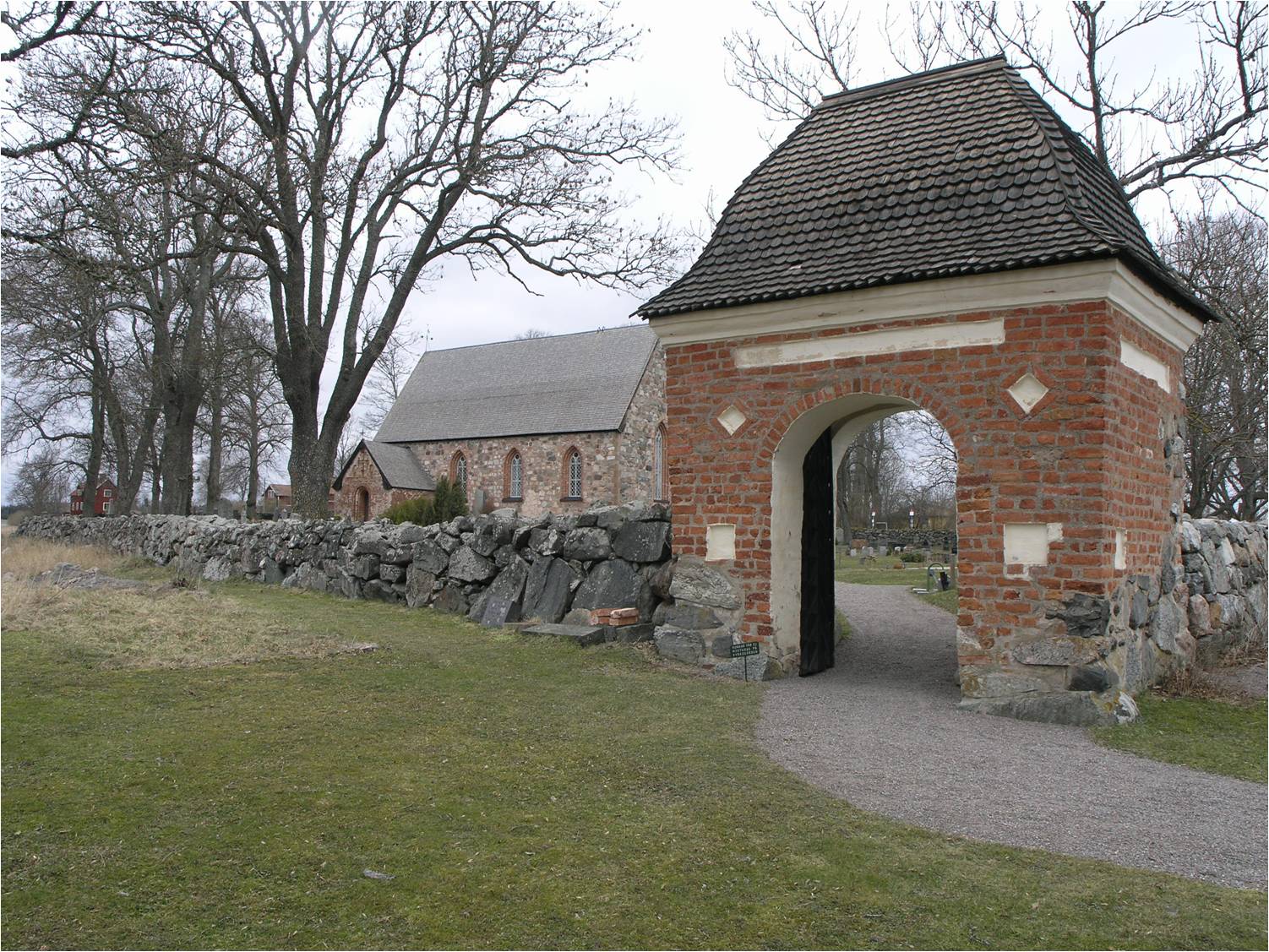 Stiglucka av tegel med spåntäckt karnisformat tak uppförd under åren 1691-92 i bogårdsmurens sydvästra hörn. 