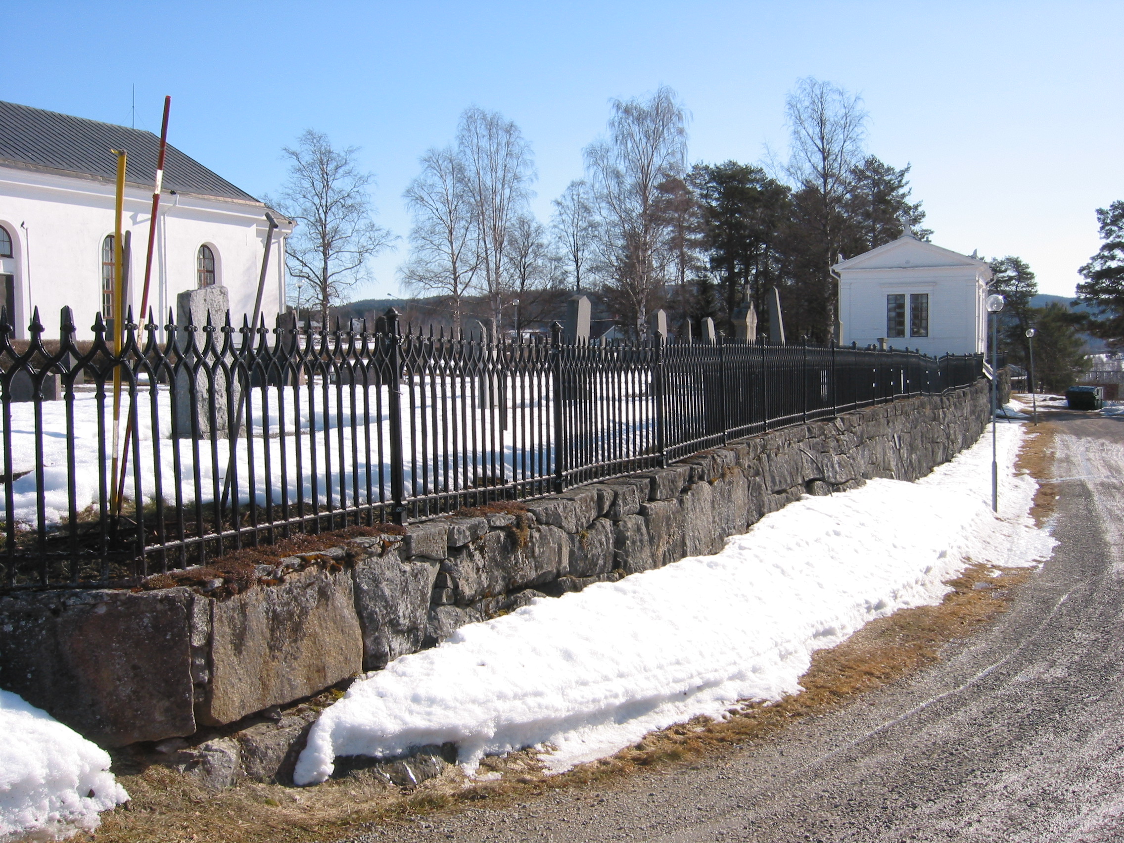 Bjärtrå kyrka med omgivande kyrkogård samt gravkapellet, södra tomtgränsen med staket & mur, vy från sydväst. 