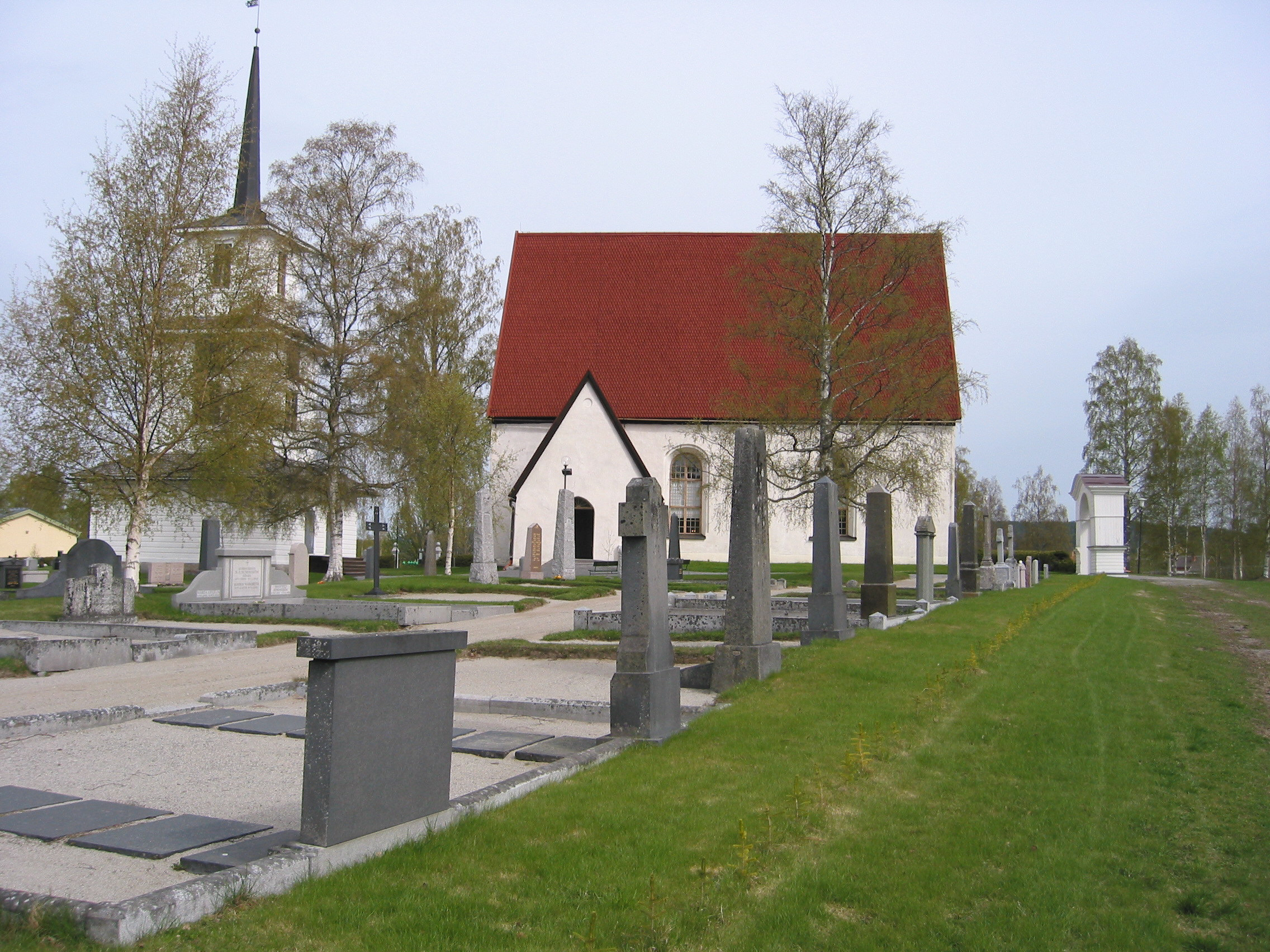 Sidensjö Kyrka med omgivande kyrkogård samt klockstapel, vy från sydöst.
