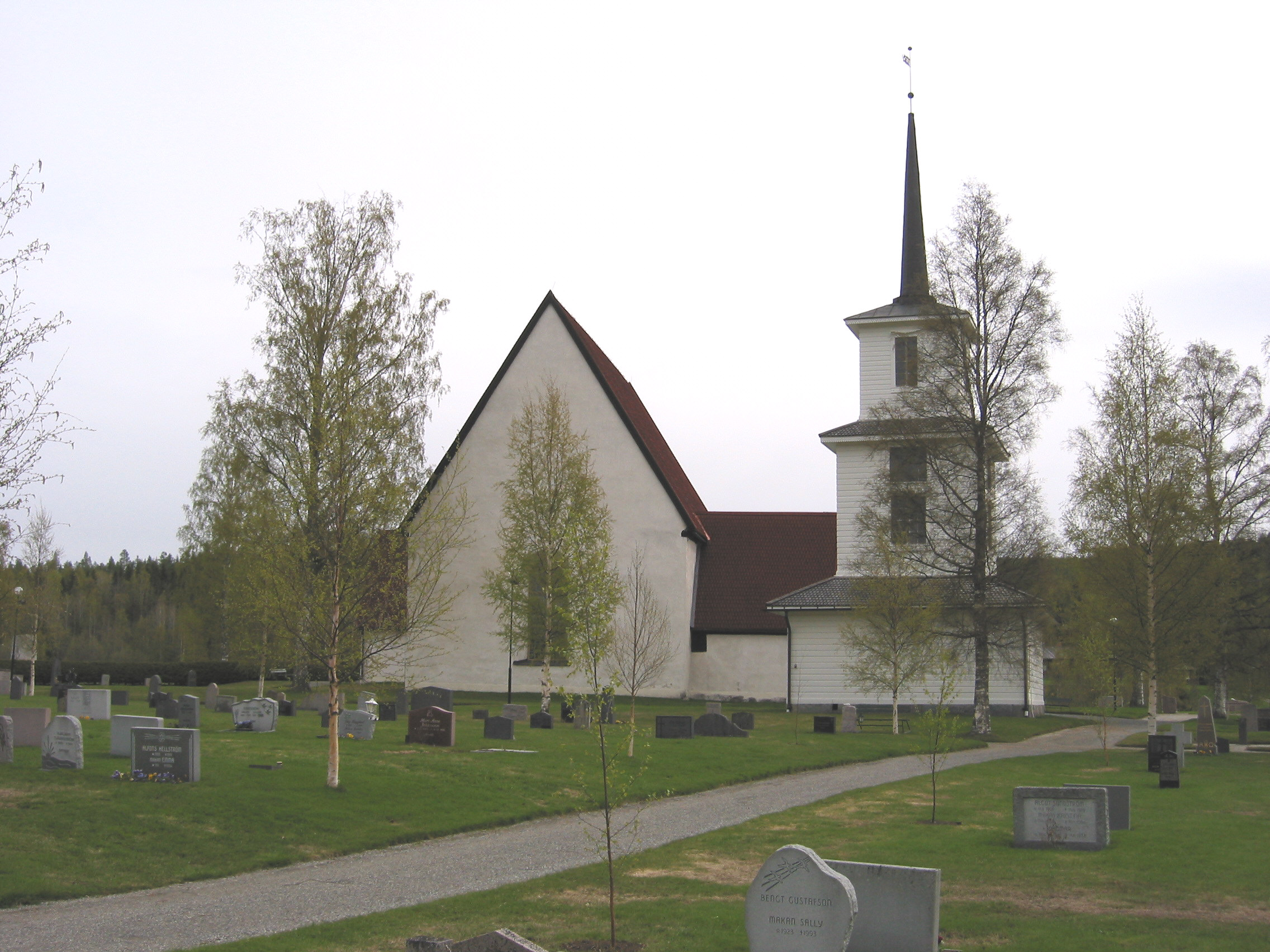 Sidensjö Kyrka med omgivande kyrkogård samt klockstapel, vy från väst.