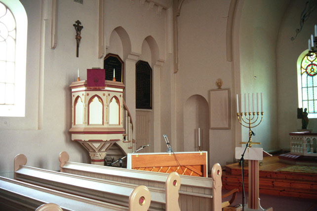 Predikstolen vid norra långväggen intill dörren till sakristian.