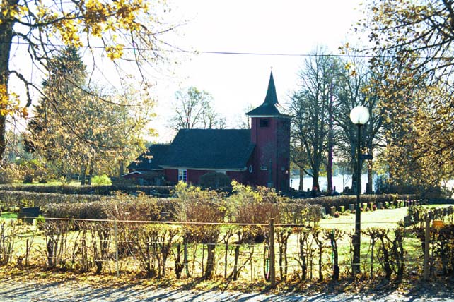 Kyrkan och kyrkogården från nordväst. I bakgrunden sjön Nären.