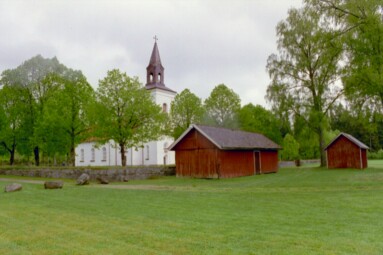 Tämta kyrka med tillhörande ekonomibyggnader, sett från fotbollsplanen i väster.