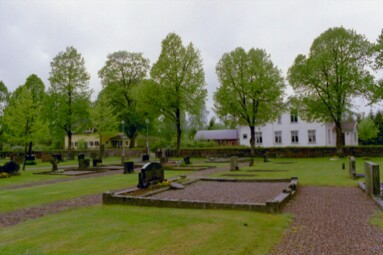 Tämtas nordvästra del av kyrkogården med församlingshemmet/skolan till höger i bild och den privata villan skymtande till vänster.
