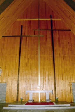 Sjöbo kyrkas altare står på ett podium vid nordöstväggen, vilken pryds av tre takhöga kors.