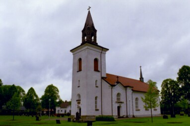 Tämta kyrka sedd från söder. Vertikaliteten betonas av takryttaren över koret och lanterninen, fasadpelarna och den brutna takfoten över sidoentréerna.