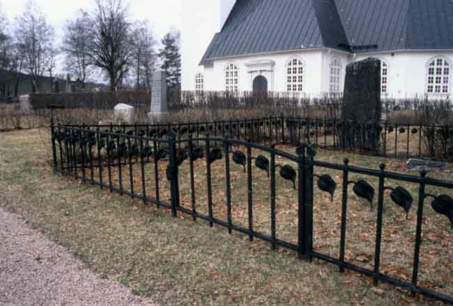 Del av smitt staket kring en gammal gravvård öster om kyrkan.