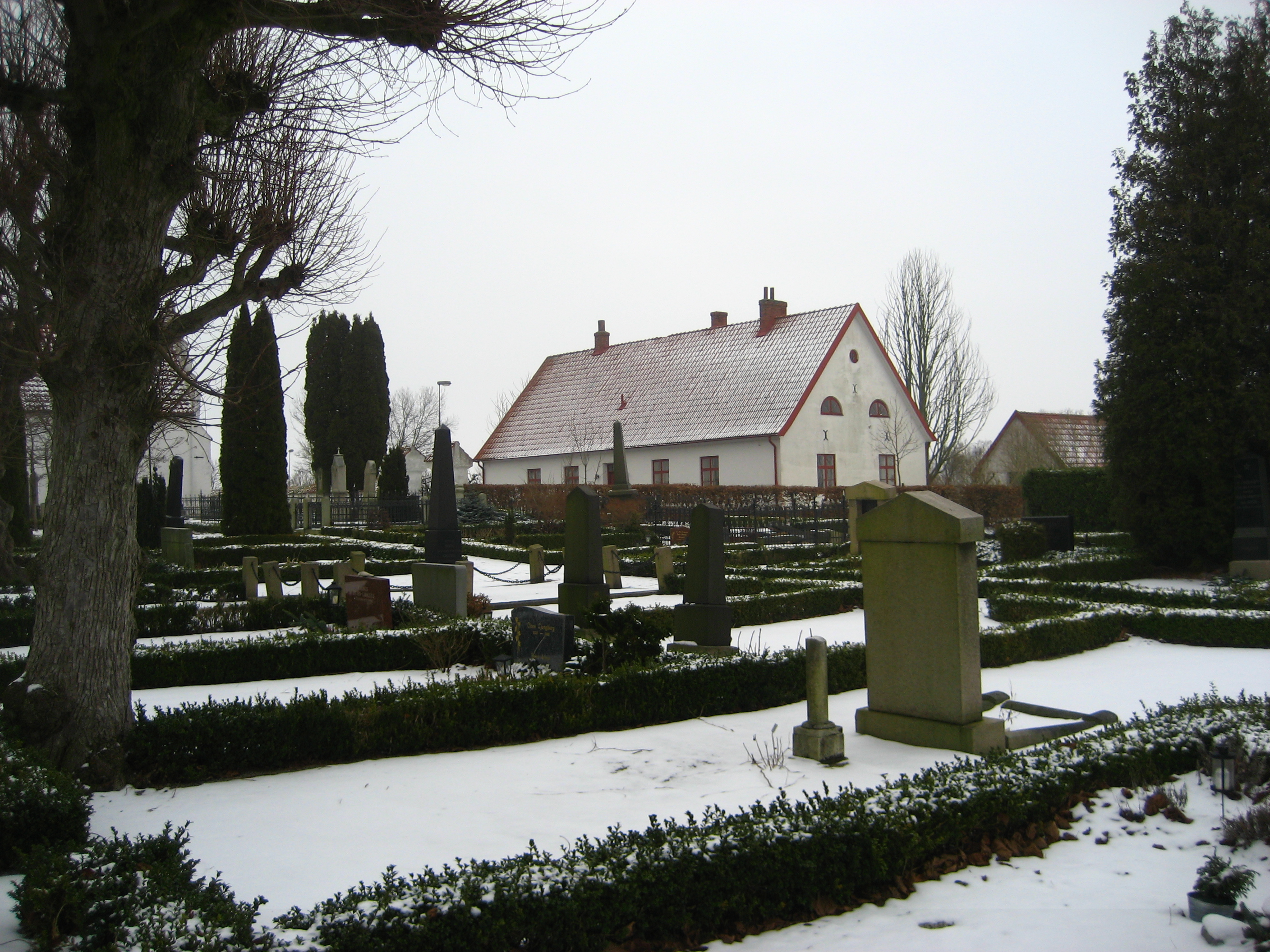 Burlövs kyrkogård nordöstra delen med gamla skolan i bakgrunden.