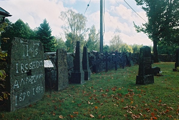 Äldre gravstenar och järnkors resta invid den östra kyrkogårdsmuren, från N.