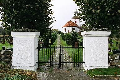 Ingång i den östra kyrkogårdsmuren med Istorps kyrka i bakgrunden, från Ö.