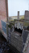 Vattnet leddes in i en intagskanal av betong med ett manuellt rensat intagsgaller. Kanalens vänstra vägg har en försänkning/ett utskov försedd med en spettlucka av trä. 
