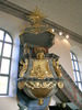 Brunflo kyrka, interiör, kyrkorummet, predikstolen.

Predikstolen från 1786 är tillverkad av Johan Edler från Lockne som även utfört altaruppsatsen. Predikstolen är placerad på norra korväggen, mellan två fönster. Den harmoniserar i färgerna med läktaren, orgeln och altaruppsatsen vilket ger kyrkorummet en helhetskänsla. Bakom predikstolen en blå draperimålning i trä från 1791 med målade guldfransar vilken går ut något över fönsternischen samt under korgen och över ljudtaket. Draperingen binder ihop korgen och ljudtaket. Ljudtaket är rikt dekorerat och kröns av en strålsol. Taket är byggt i två nivåer. Det är förankrat i väggen bakom med en järnstång. Ljudtaket har invändigt ett plant målat tak i ljust grått med brytning av blått. Takets överhängande kanter är vackert utskurna ur träet samt festongerna. Alla detaljer är förgyllda. Korgen är tresidig med sidofälten rikt dekorerade med förgyllningar i relief. Ovan varje spegel sitter ett änglahuvud. Korgens överliggare är marmorerad och utkragad och på vilken ett marmorerat bokstöd är fäst liksom ett timglas. Tidigare fanns också en döskalle på timglaset som dock stals för ca 10 år sedan. Den nedre delen av korgen börjar med en marmorerad utkragad list på vilken det under är fäst snäckskal samt bladornamentik. Korgens underdel är korgimiterad och avslutas med en rundel. Korgen är förstärkt med två järnbalkar i norrväggen och in under korgen. 1981 upptäcktes att de befintliga träbjälkarna börja släppa från väggen. 1982 byttes de ut mot nu befintliga järnbalkar och predikstolen konserverades samma år. 

Bilderna är tagna av Christina Persson & Isa Lindkvist, bebyggelseantikvarier vid Jämtlands läns museum, i samband med inventeringen, 2005-2006.